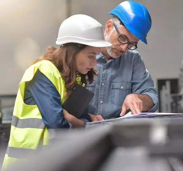 Engineer with blue helmet explaining construction plan to project manager on-site